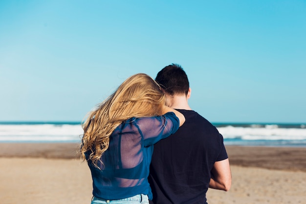 모래 해변에 서있는 익명 커플