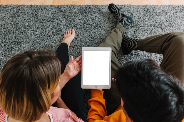 Faceless couple using tablet on carpet