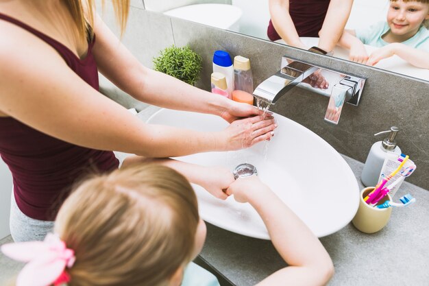 Faceless girl and woman washing hands