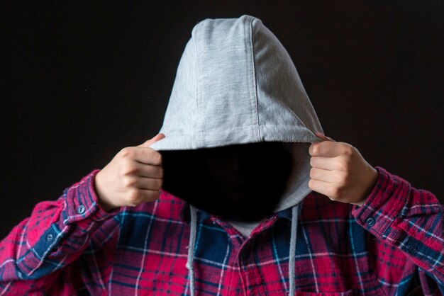 赤い背景のフードに顔のない男のシルエットaf男 匿名の犯罪の概念 プレミアム写真