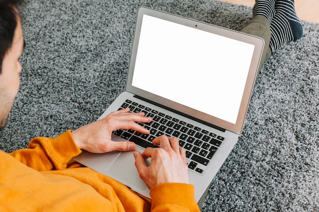 Faceless man browsing laptop on floor