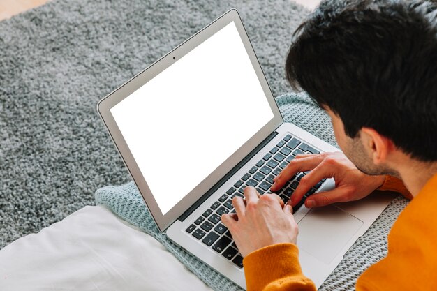 Faceless man using laptop on bed