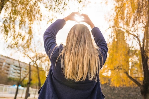 Foto gratuita modello senza volto che mostra il cuore al sole