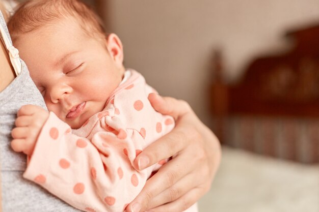 若い白人の父親が彼女の女の赤ちゃんに牛乳を与え お父さんの手で生まれたばかりの泣いている幼児の女の子 口の中で子供のなだめるような疲れた男 黄色い壁の上に孤立して立っています プレミアム写真