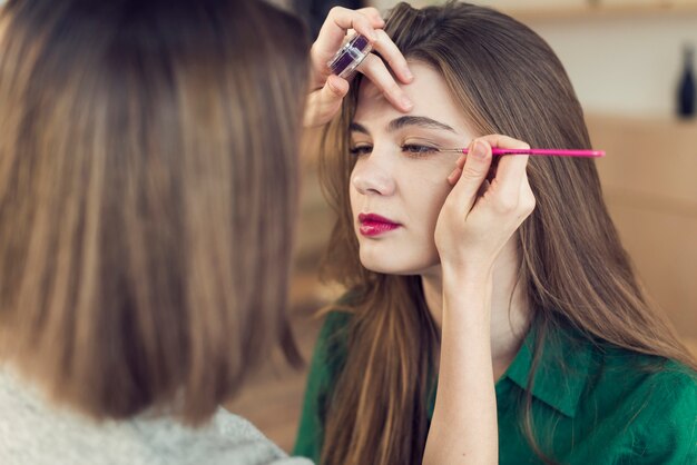 Faceless stylist applying eyeliner on model