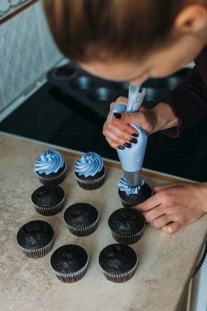 Foto gratuita donna senza volto decorando cupcakes