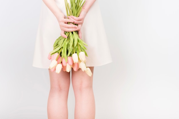 Faceless woman hiding bouquet behind back