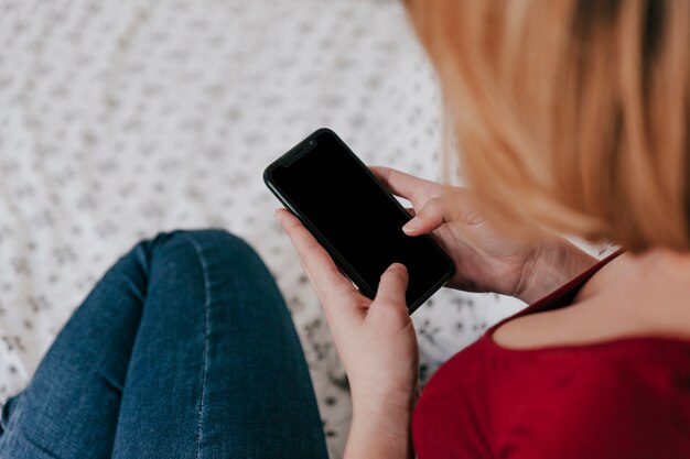 Faceless woman using smartphone on bed