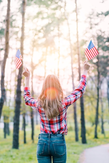 日差しの中でアメリカ国旗を持つ顔のない女性