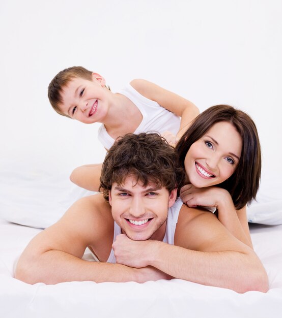 ベッドに横たわっている幸せで楽しい家族の顔