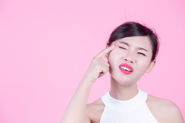 Facial skin problems women - unhappy young women touching her skin on a pink background.