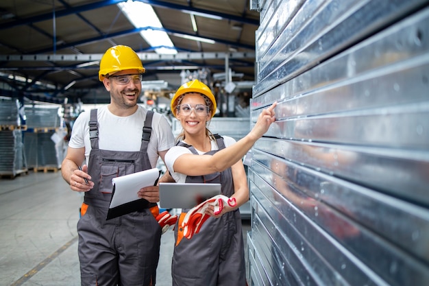 Factory employees checking quality of metal products in production plant