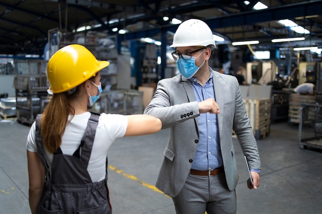 Factory manager and worker greeting each other with elbow bump due to global corona virus pandemic and danger of infection