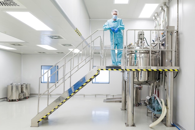 Factory worker standing on ladder far loor