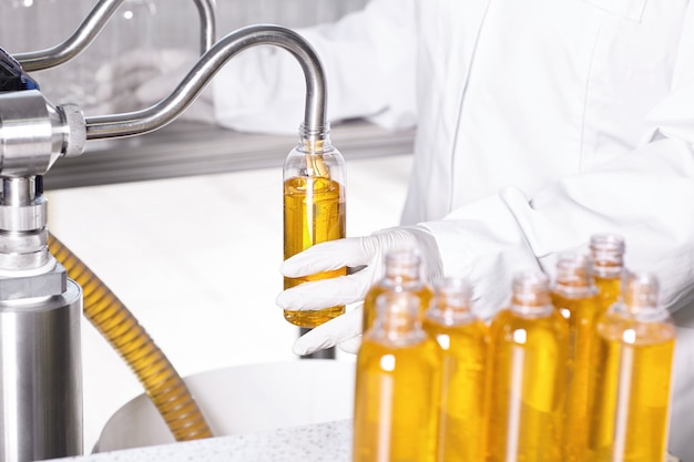 Free photo factory worker in white gown and rubber gloves holding plastic bottle