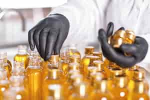 Free photo factory worker in white gown and rubber gloves screwing bottle caps