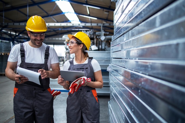 Factory workers walking in industrial plant and discussing about production efficiency