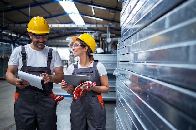 Free photo factory workers walking in industrial plant and discussing about production efficiency