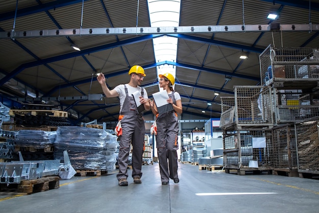 Free photo factory workers walking through large production hall and having conversation