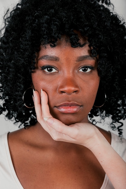 Fair hand touching the chin of an african woman looking at camera