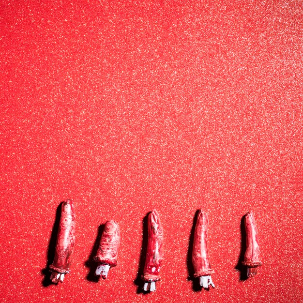 Fake scary fingers over red glitter background