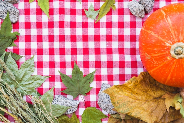 Fall composition with dried leaves on checkered tablecloth