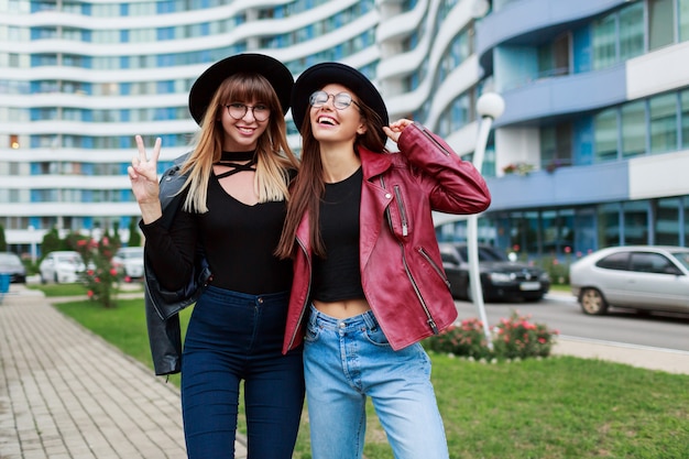 Fall fashion look.  Couple of attractive graceful girls in cute round glasses and black hats posing