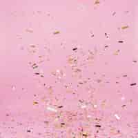 Free photo falling golden confetti on pink background