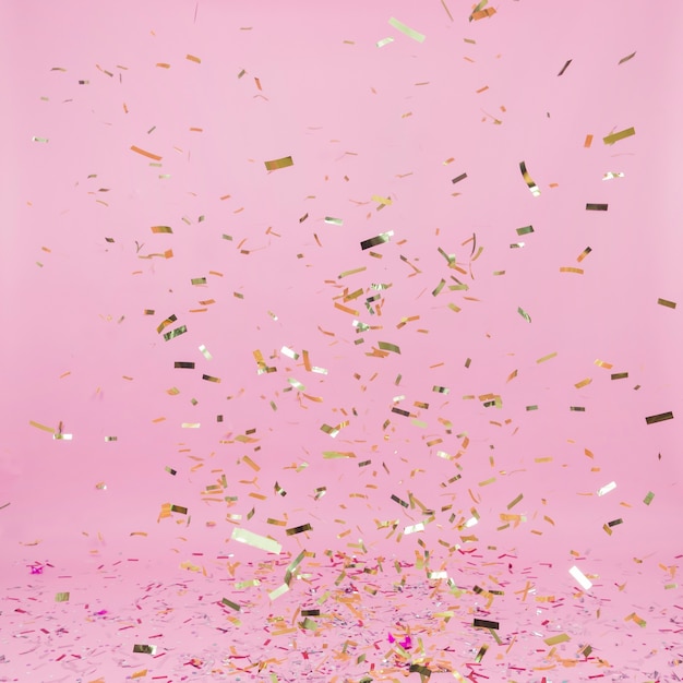 Falling golden confetti on pink background