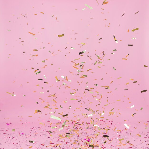 Falling golden confetti on pink background