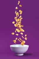 Free photo falling granola in bowl. healthy breakfast ingredients. flying food on purple background. still life. copy space