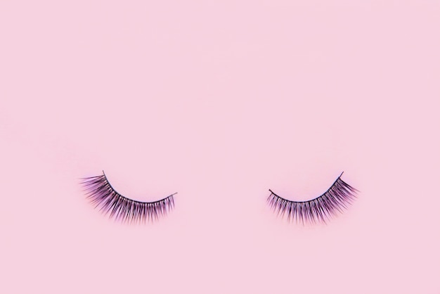 Premium Photo | False eyelashes on pink colour with copy space