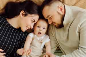 Free photo families portrait of happy young mother and father with child posing in home interior