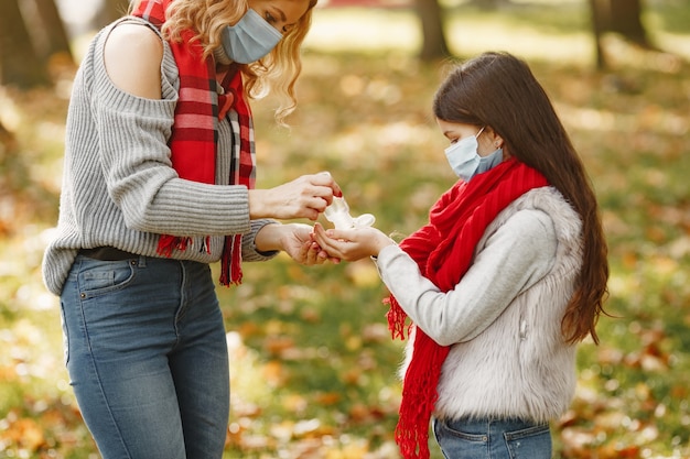 秋の公園の家族。コロナウイルスのテーマ。娘と母。人々は防腐剤を使用します。