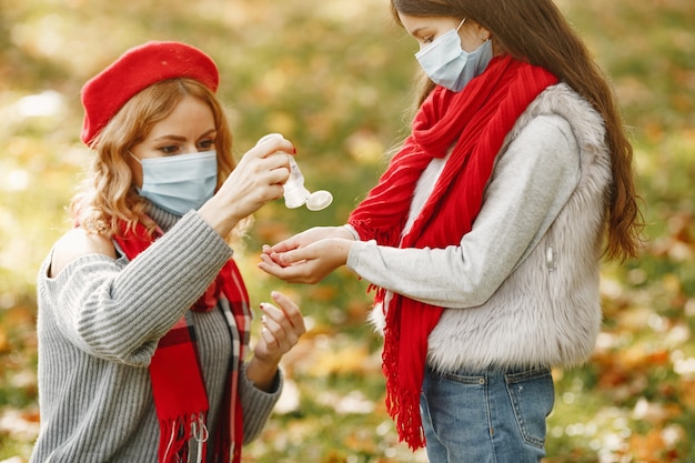 秋の公園の家族。コロナウイルスのテーマ。娘と母。人々は防腐剤を使用します。