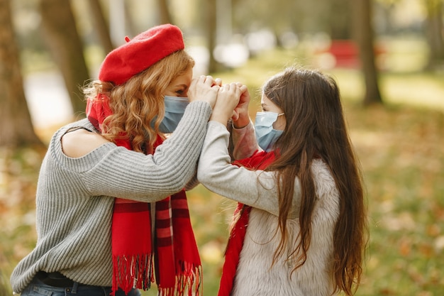 Family in a autumn park. Coronavirus theme. Mother with daughter.