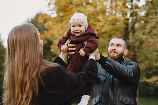 Famiglia in un parco d'autunno. uomo in giacca nera. bambina sveglia con i genitori.