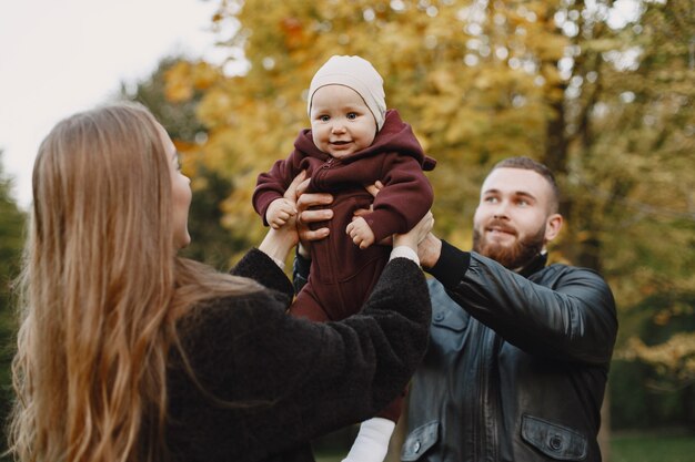 Family in a autumn park. Man in a black jacket. Cute little girl with parents.