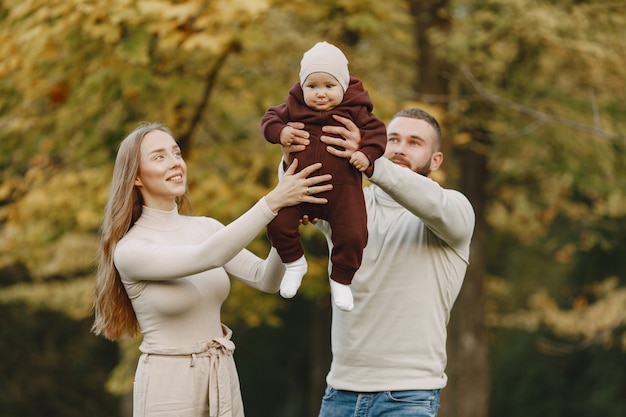 Семья в осеннем парке. Мужчина в коричневом свитере. Милая маленькая девочка с родителями.