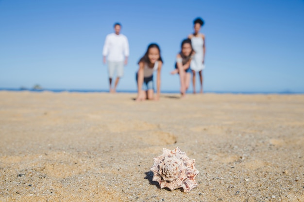 前景に貝殻を持つビーチの家族