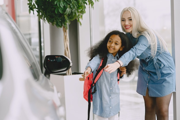 Free photo family in a car salon. woman buying the car. little african girl with mther.