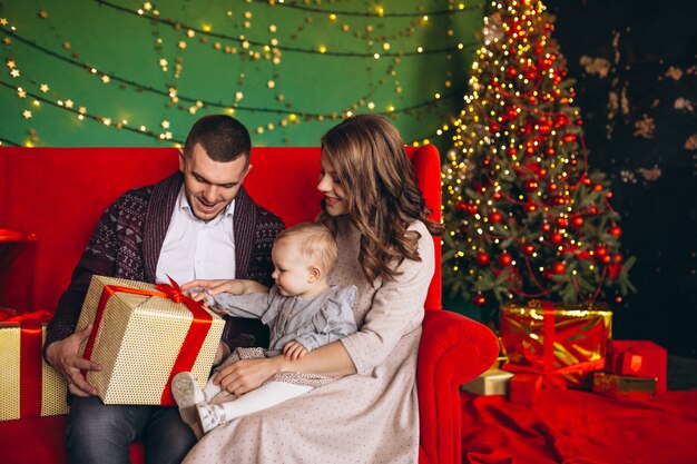 Family on Christmas sitting on red sofa by christmas tree