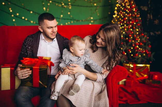 Family on Christmas sitting on red sofa by christmas tree