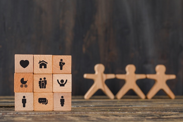 Family concept with icons on wooden cubes, human figures on wooden table side view.