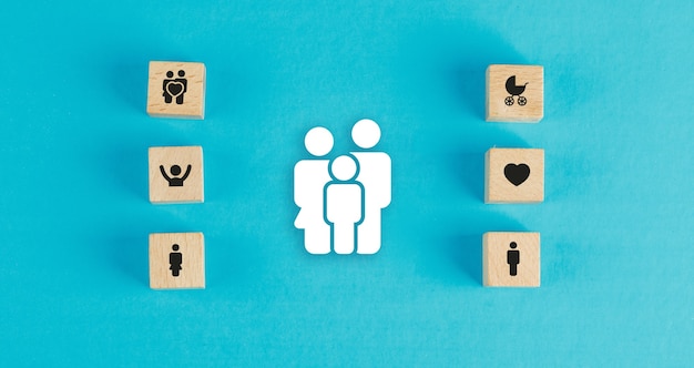 Family concept with wooden blocks, paper family icon on blue table flat lay.