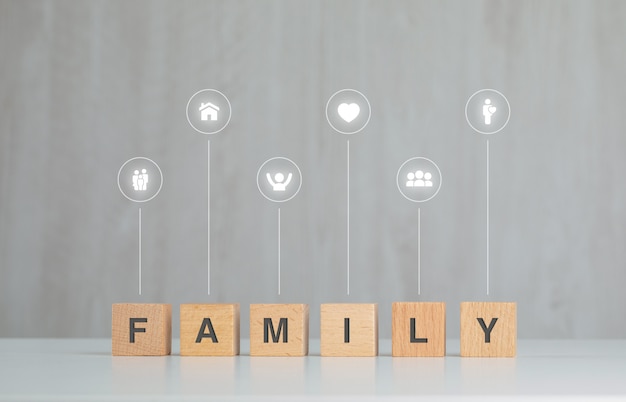 Free photo family concept with wooden cubes, icons on grey and white table side view.