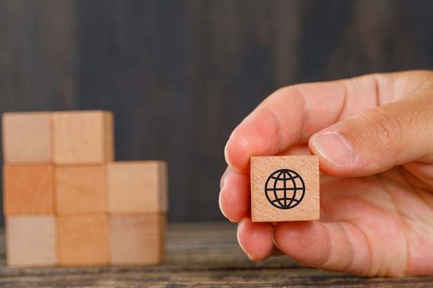 Family concept on wooden table side view. hand holding wooden cubes with icons.