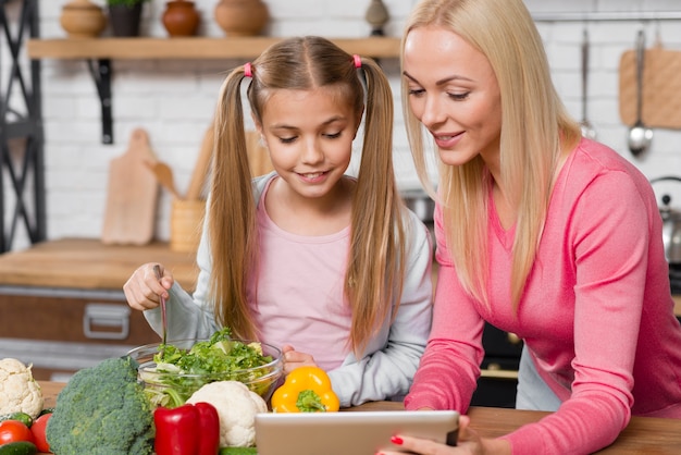 Семья готовит на кухне и смотрит на планшет