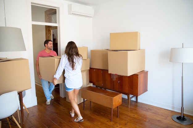 Family couple leaving their apartment, carrying carton boxes and furniture