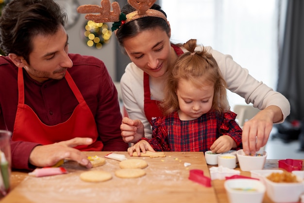 キッチンで一緒にクリスマスクッキーを飾る家族